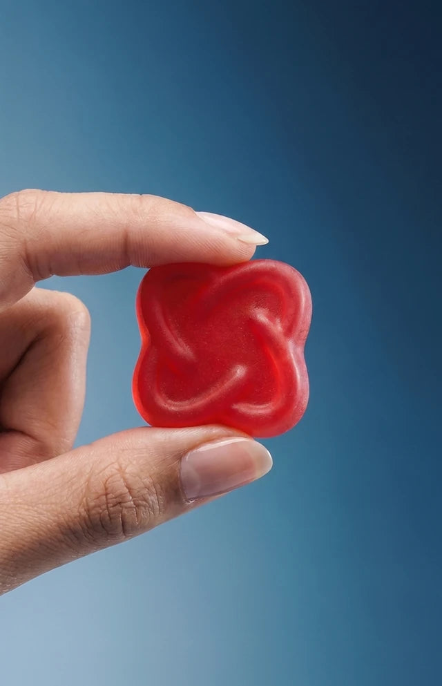 Hand holding an Arq8 strawberry gummy